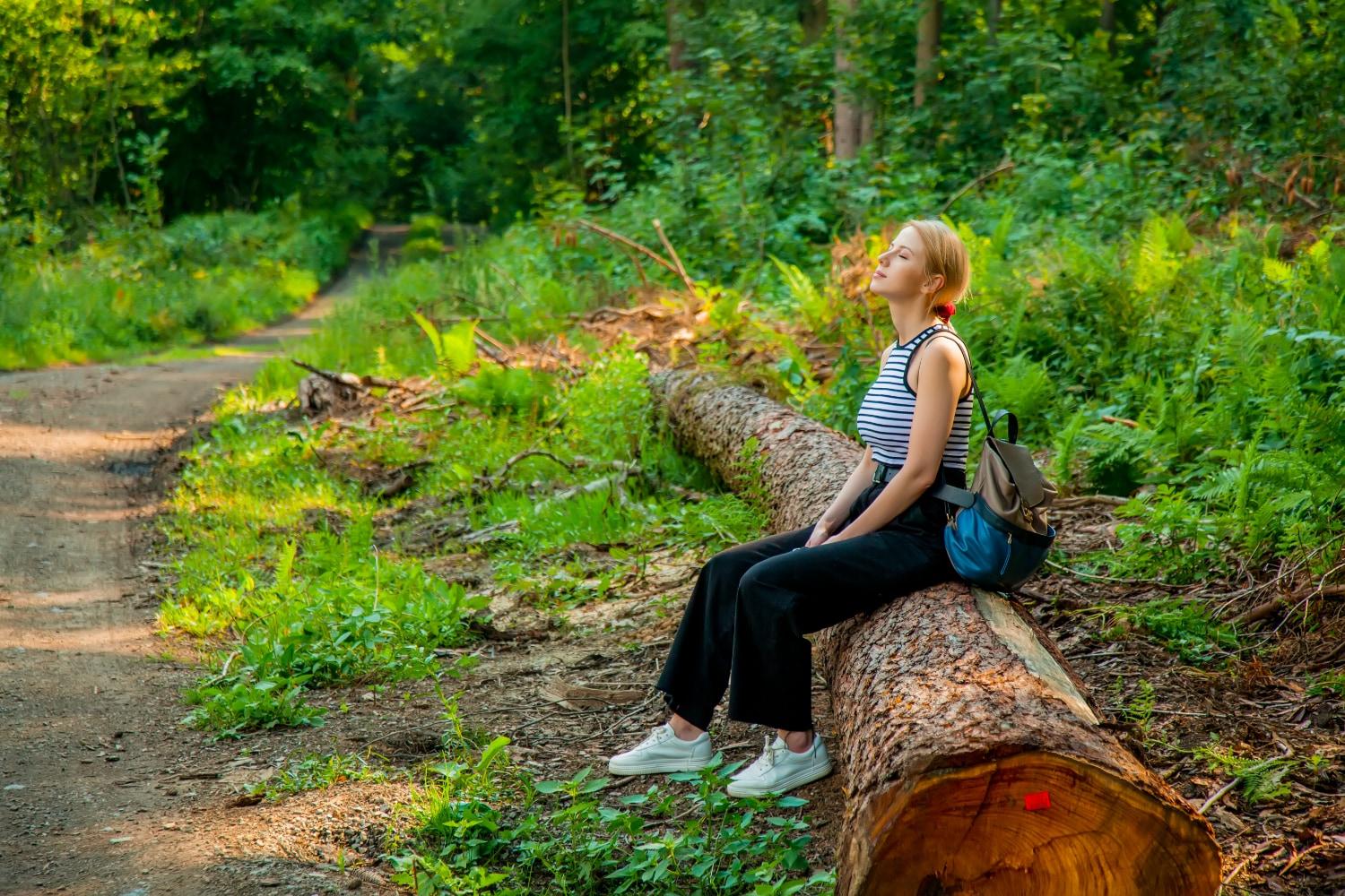 A woman siting on a log in the forest